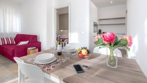 Een moderne woonkamer met een rode bank, een eettafel met borden, glazen en een fles wijn.