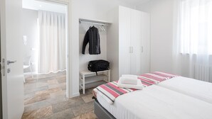 Een hotelkamer met een bed, een kledingkast, een bank met een tas en een stoel.