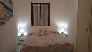 Une chambre à coucher avec un lit, deux lampes de chevet, une fenêtre avec des rideaux et un tableau accroché au mur.