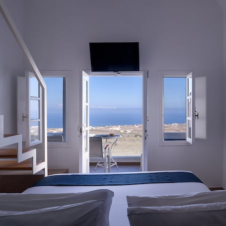 A bedroom with a bed, a desk, and a view of the sea.