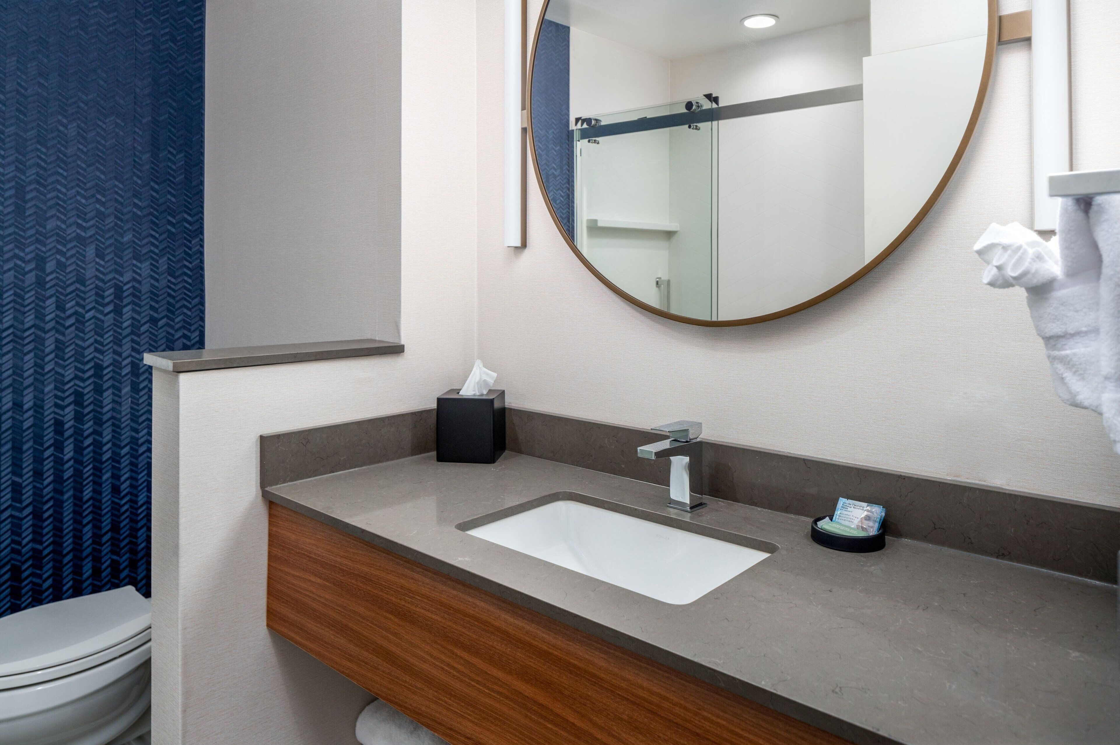 A bathroom with a white sink, a mirror, and a towel hanging on the wall.
