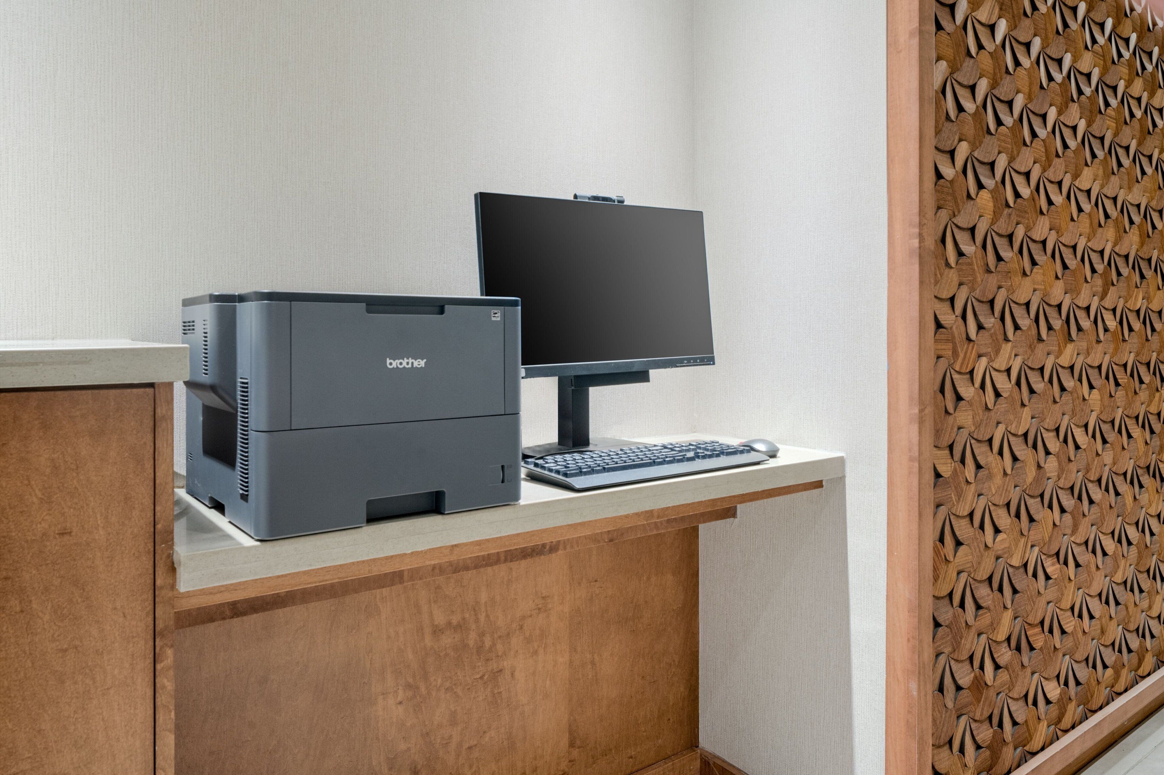 Un escritorio con una impresora Brother, un monitor y un teclado.