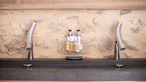 A bathroom with a stone wall, two faucets, and two bottles of shampoo. - "Olivier" Room – Quality B&B accommodation comes in all sizes (Fayence)