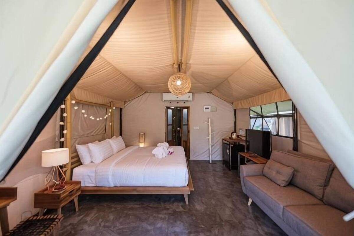 Alojamiento con carpa, cama, sofá y televisor.