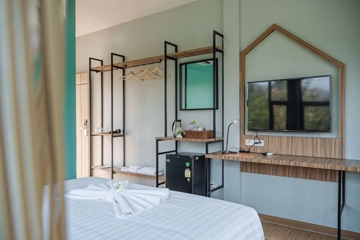 Habitació d'hotel amb un llit, una taula de treball amb un ordinador, un mirall i una finestra.