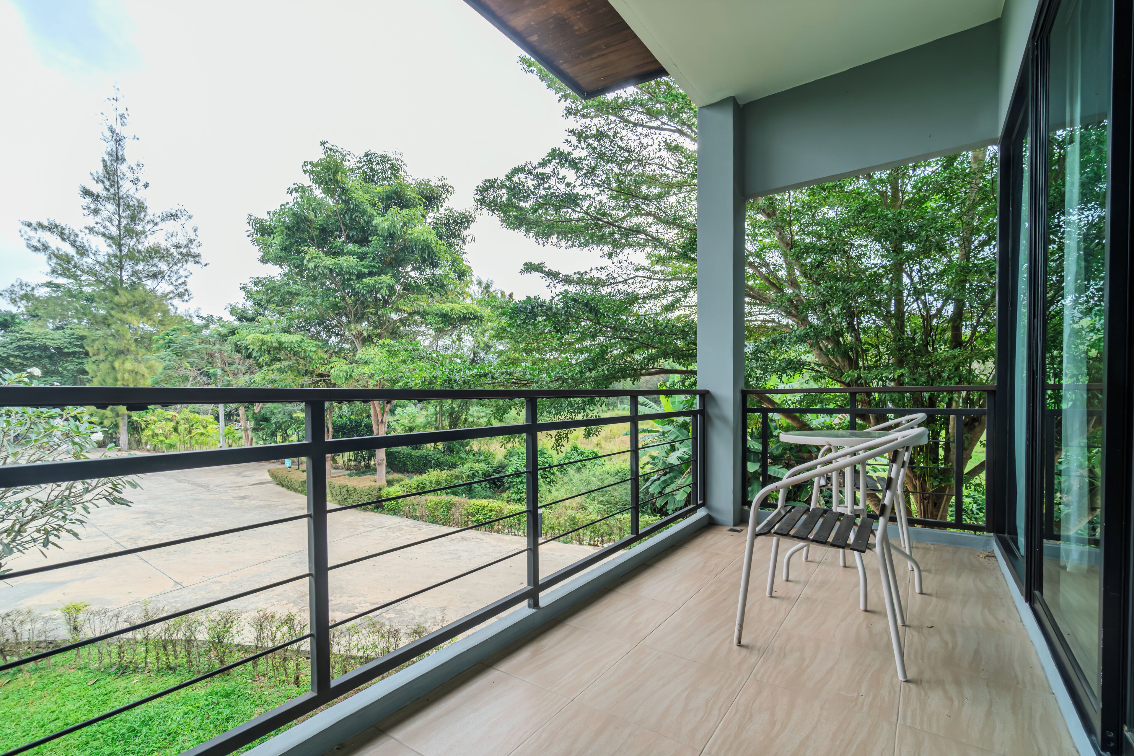 Un balcone con vista su un giardino e degli alberi.