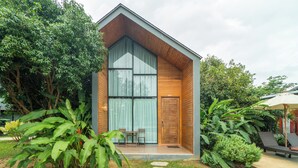 A modern building with a large window, a door, and a small outdoor seating area. - The Tree Riverside Resort Kaeng Krachan (Kaeng Krachan)