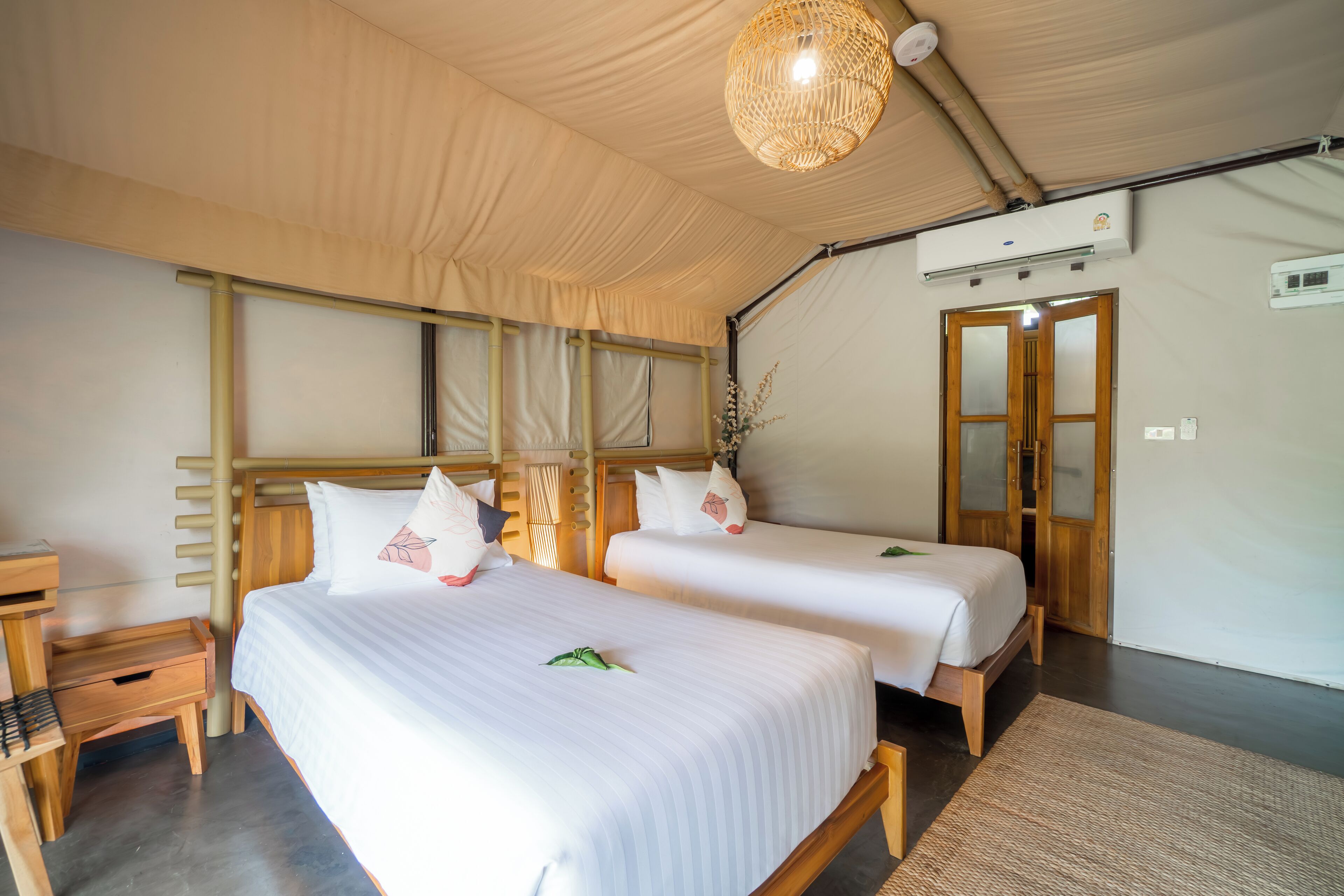 A room with two beds, wooden headboards, a ceiling fan, and a door with glass panels.