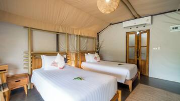 A room with two beds, wooden headboards, a ceiling fan, and a door with glass panels.