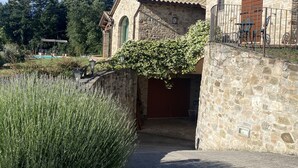 Un edificio in pietra con un giardino, una piscina e una zona relax all'aperto coperta.