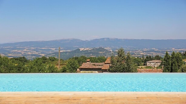Una piscina con vista su montagne lontane e alcuni edifici.