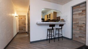 Une cuisine moderne avec des meubles en bois, un plan de travail et deux tabourets de bar.