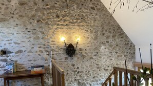 A rustic stone wall with a wooden staircase and a wall-mounted light fixture. - Cozy rental in Blomard with shared pool and pet-friendly (Blomard)