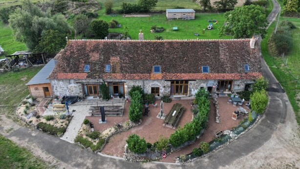 A rustic stone building with a tiled roof, surrounded by a landscaped garden with pathways and seating areas. - Cozy rental in Blomard with shared pool and pet-friendly (Blomard)