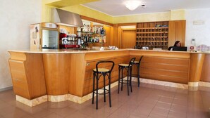 Una cuina amb una zona de bar de fusta, una màquina de cafè i una estant amb ampolles.