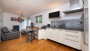 A modern kitchen with white cabinets, a stainless steel range hood, and a grey backsplash.