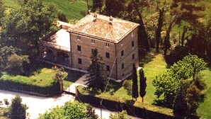 Un grand immeuble à plusieurs étages, doté d’un toit plat, entouré d’une végétation luxuriante et d’arbres.