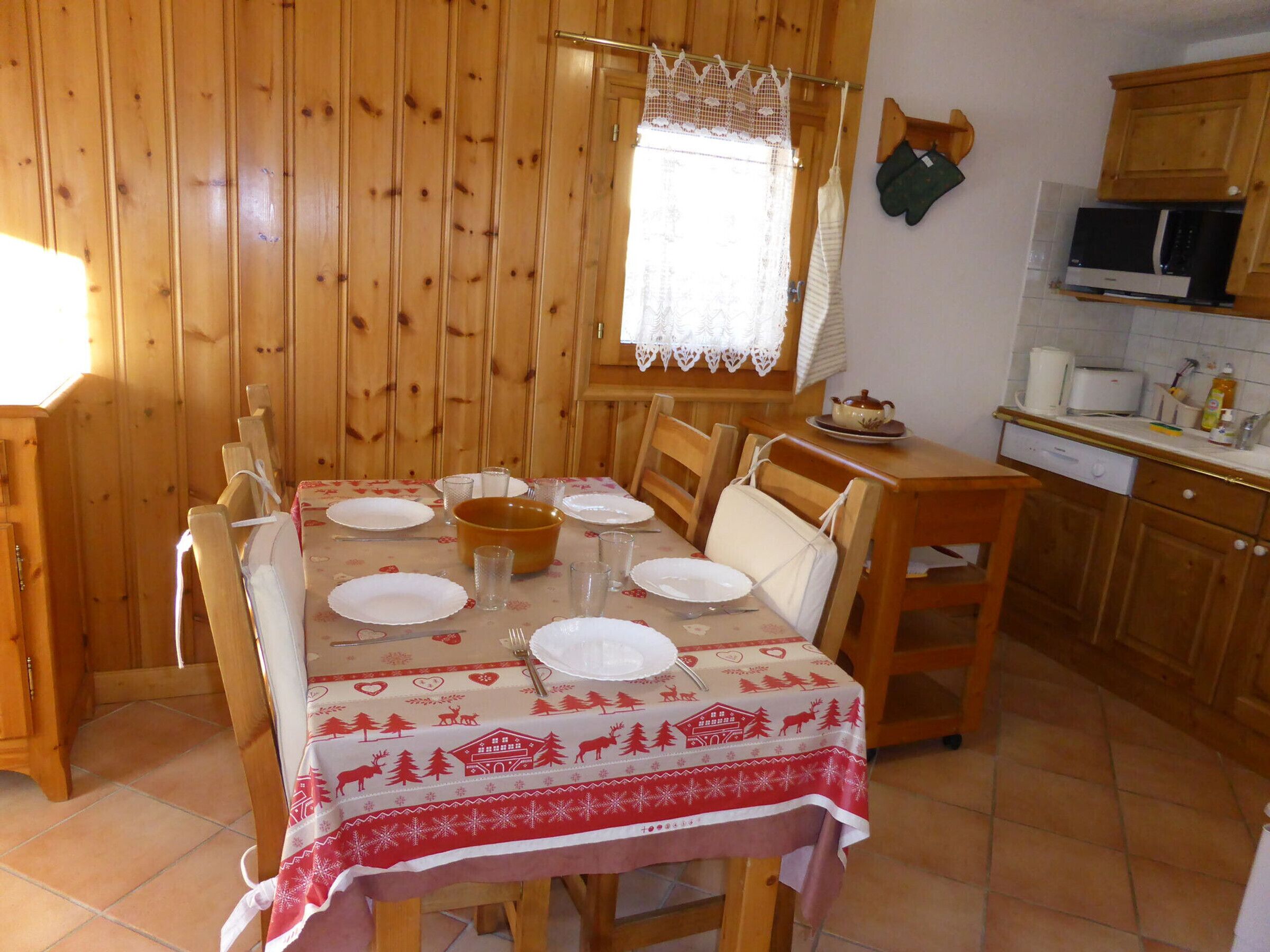 Un comedor con una mesa de madera dispuesta para seis personas, rodeada de sillas.