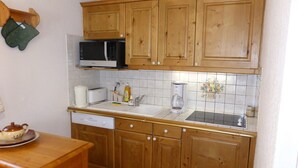 A small kitchen with wooden cabinets, a microwave, a toaster, and a sink. - 2-room cabin apartment, 6 ppl, parking in Les Contamines-Montjoie (Les Contamines-Montjoie)