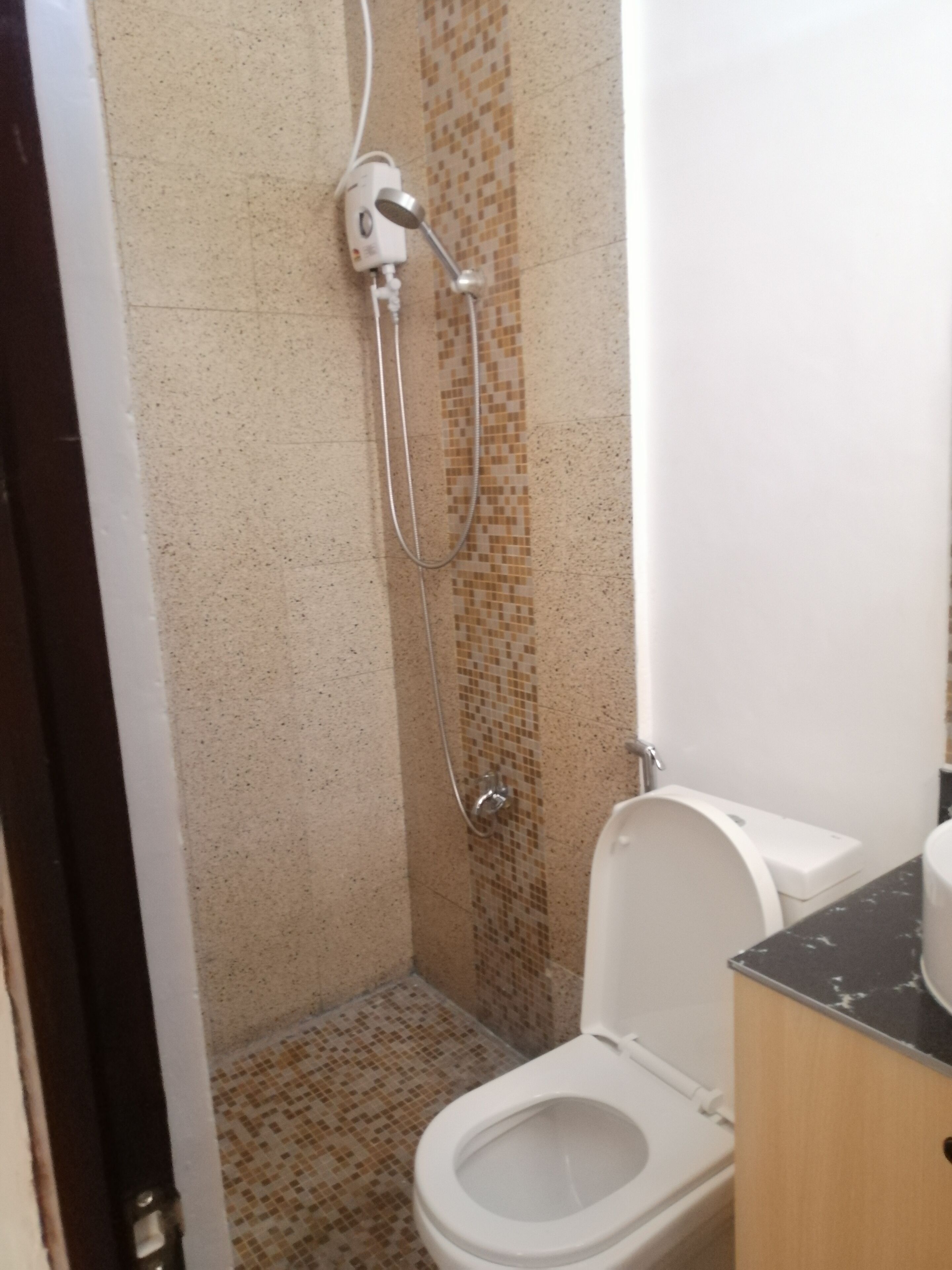 Ein Badezimmer mit Dusche, Toilette und Fliesenboden.