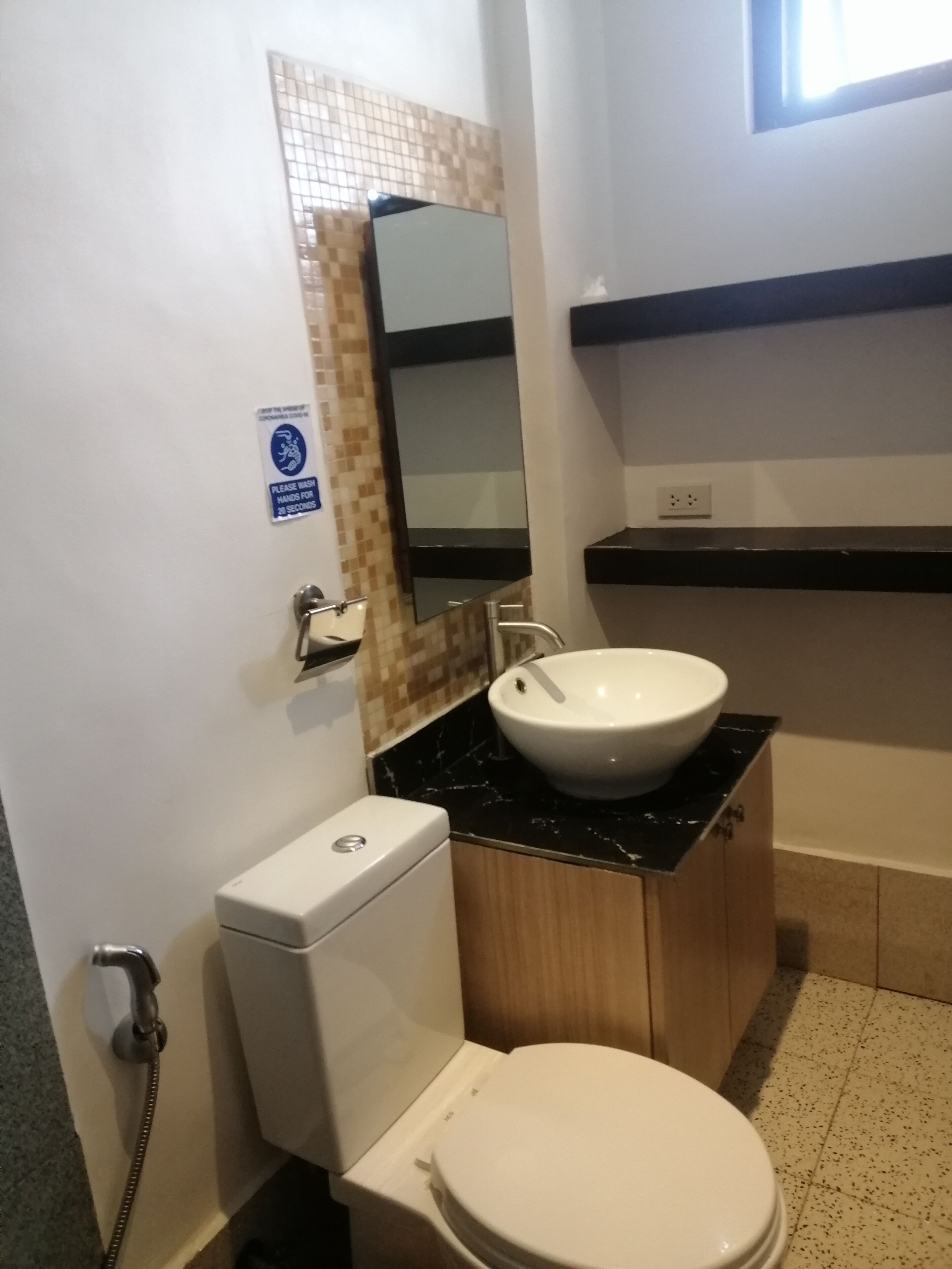 Een kleine badkamer met een toilet, een wastafel en een spiegel.