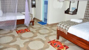 Une chambre d’hôtel avec deux lits, chacun doté d’un baldaquin, une petite table, un miroir et une étagère avec des articles de toilette.