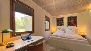 Un dormitorio con cama, escritorio, silla y dos lámparas de noche.