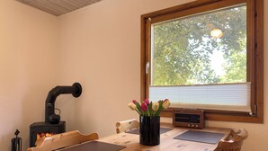 Una mesa de comedor de madera con posavasos negros, una tetera negra y un radio.