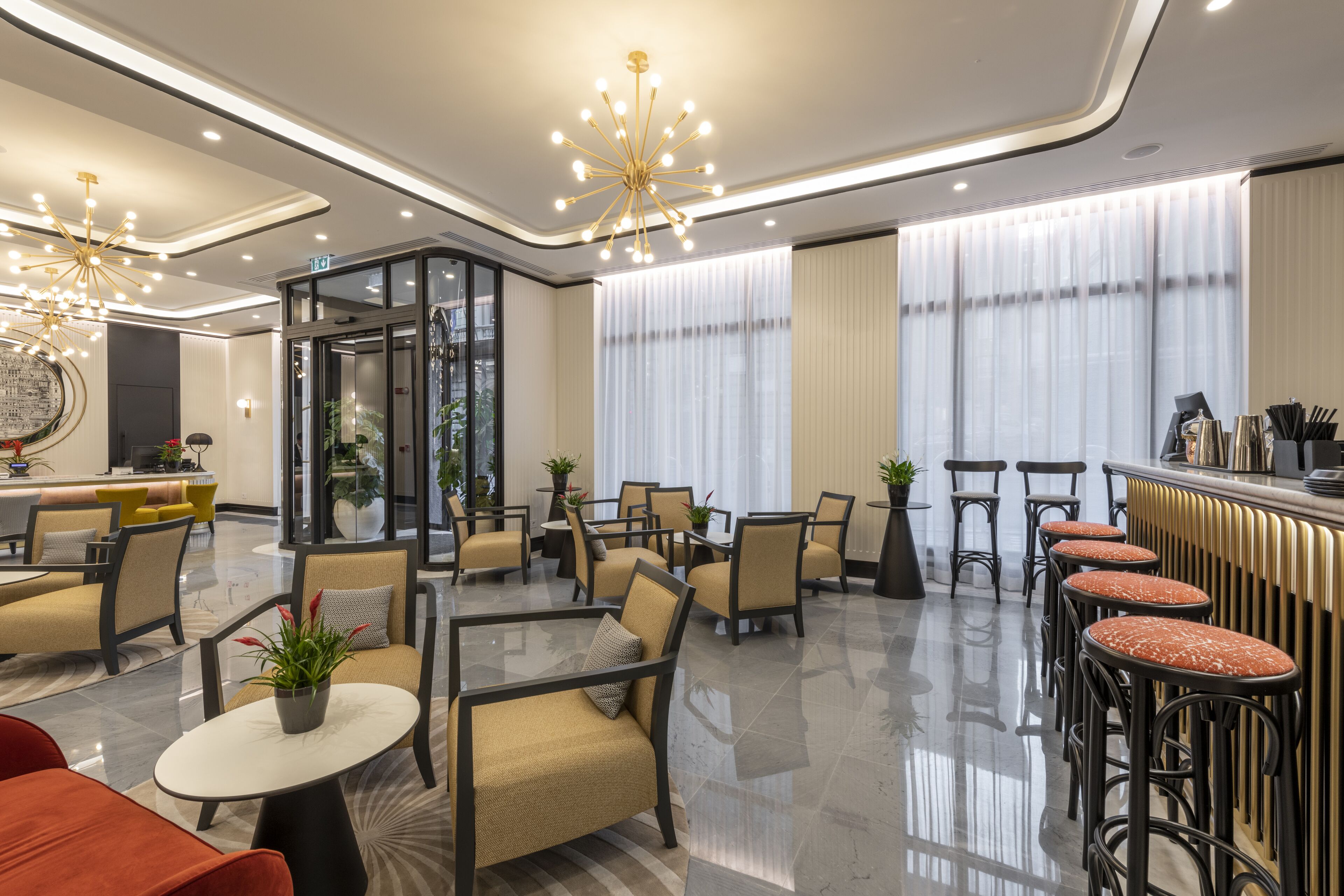 Un moderno vestíbulo de hotel con una zona de estar central, un bar con taburetes y una recepción.