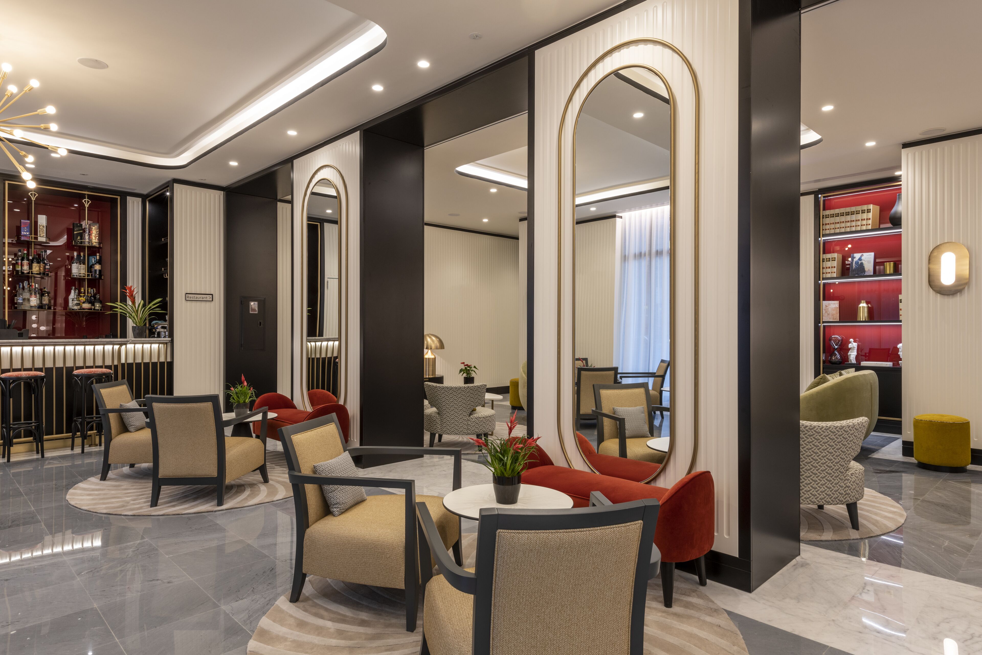 Eine moderne Hotelhalle mit Barbereich, Sitzgelegenheiten und einem großen Spiegel.