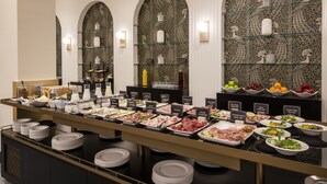 A buffet with various food options and glass shelves. - H10 Palazzo Galla (Rome)