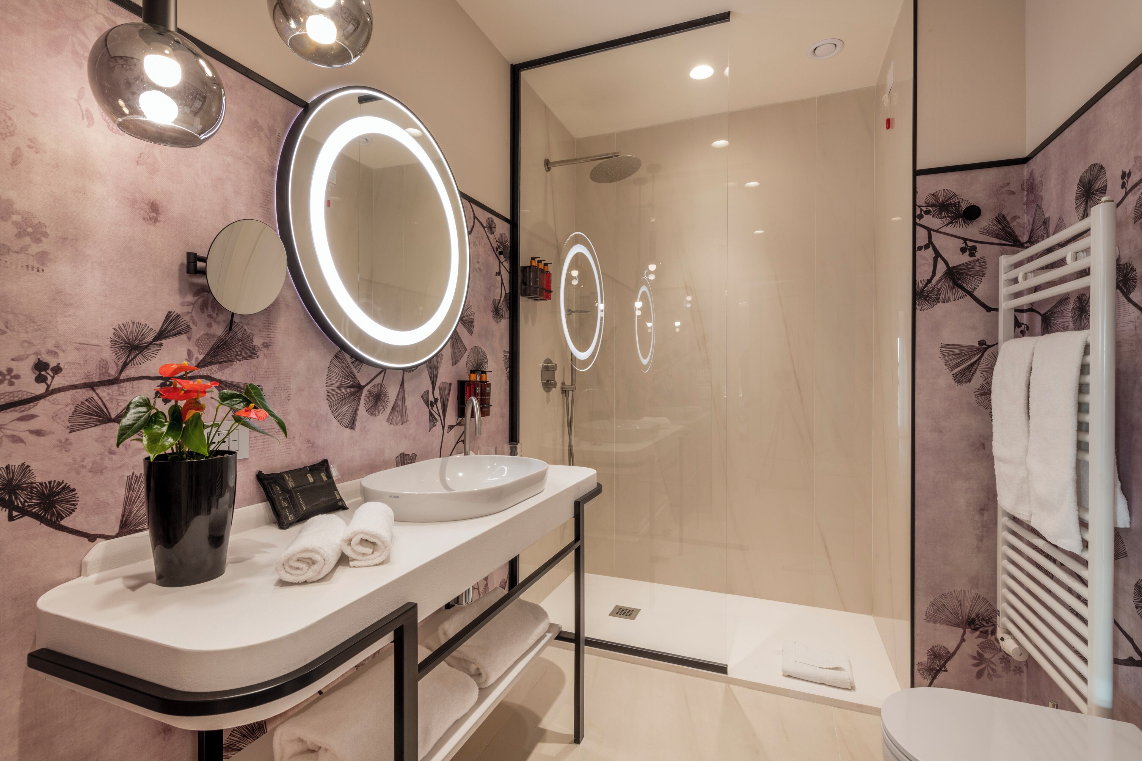 Une salle de bain moderne avec un grand miroir, un lavabo et une douche à parois de verre.