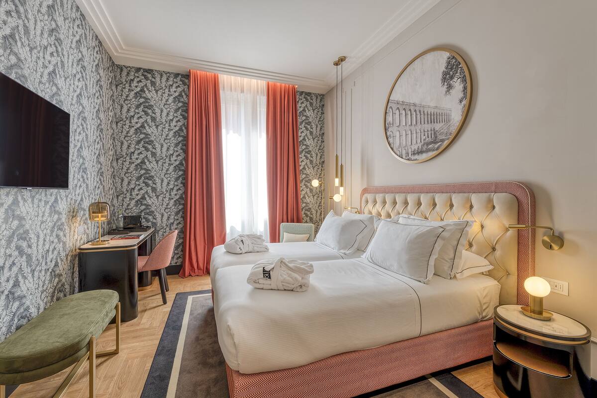 A hotel room with a large bed, a desk, a chair, and a television.