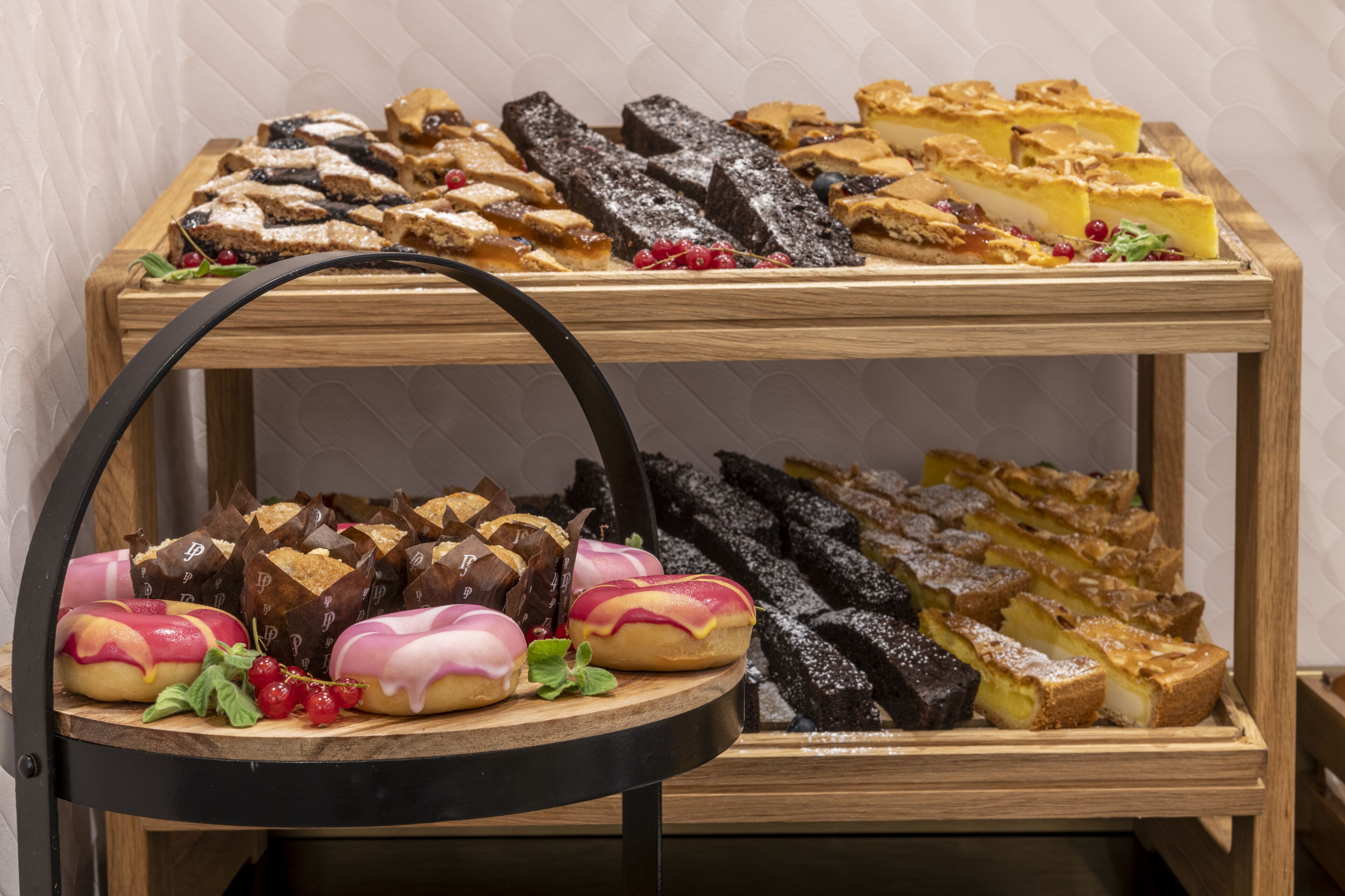 A display of assorted pastries and desserts on a wooden stand.