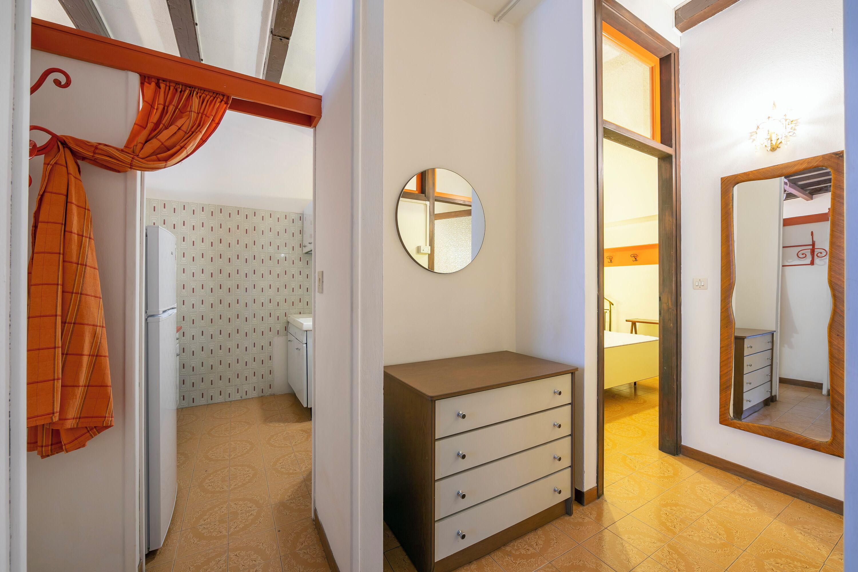 A hallway with a wardrobe, a mirror, and a door leading to a bathroom.