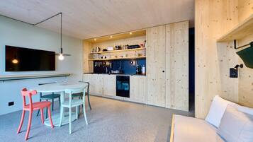 Una cocina moderna con armarios de madera, una zona de comedor con mesa y sillas, y un horno empotrado.