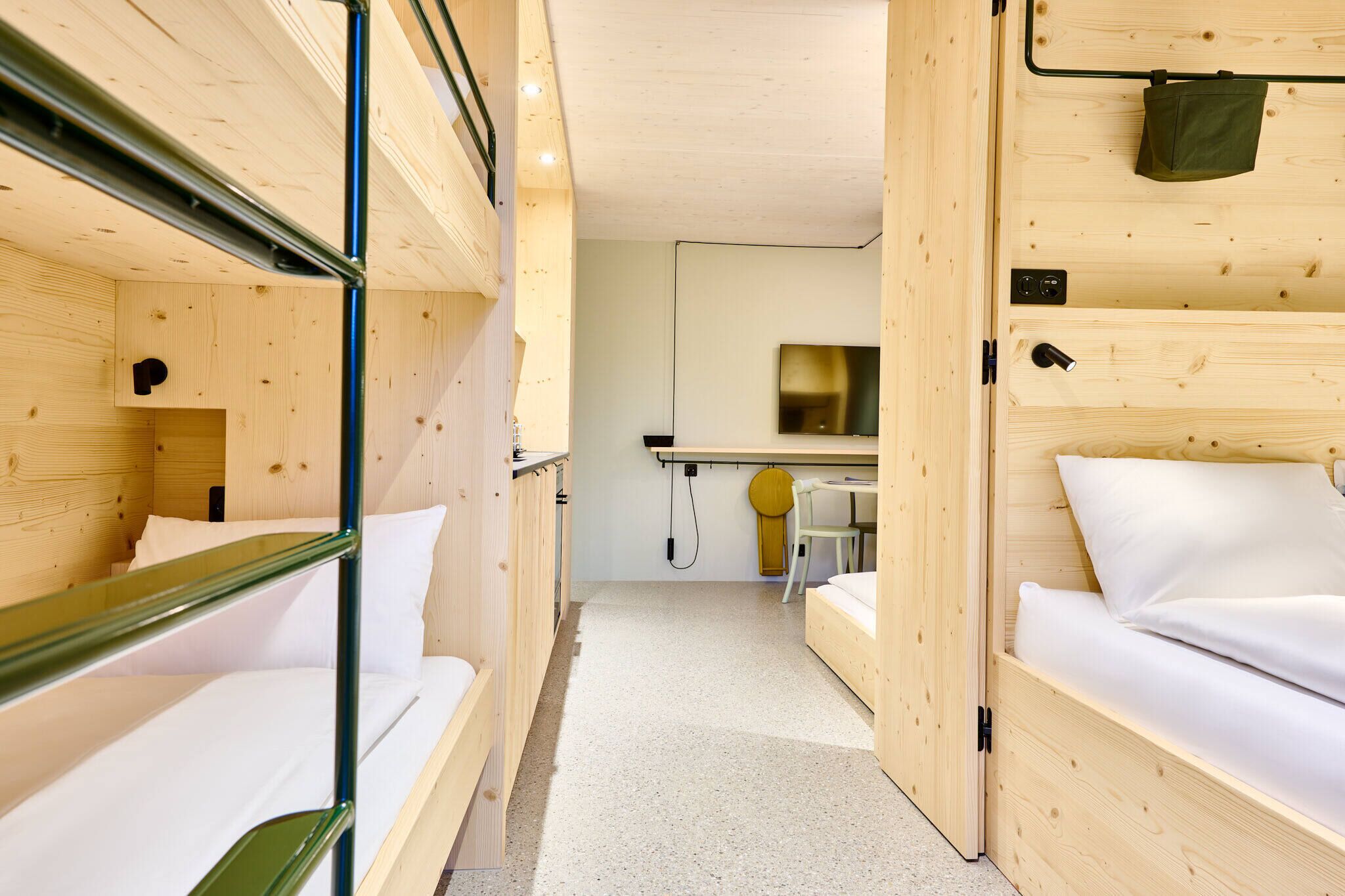 A compact hotel room with bunk beds, a small desk, and a mirror.