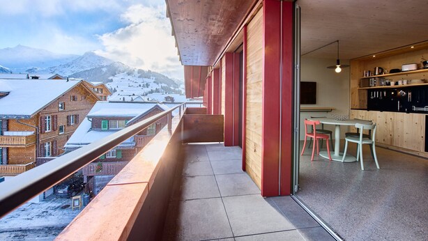 Een balkon met uitzicht op besneeuwde gebouwen en bergen.