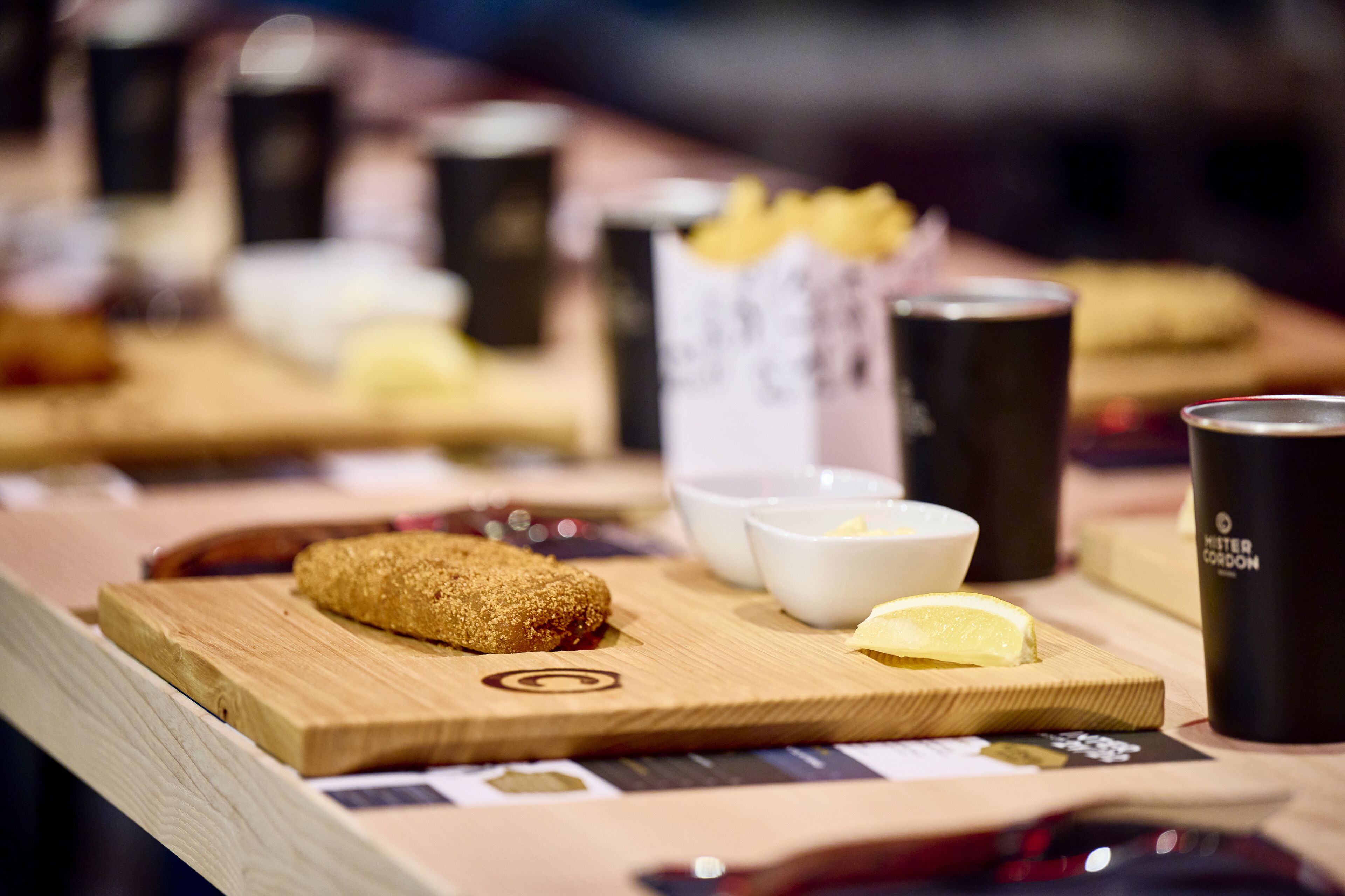 A wooden table with a croissant, a lemon wedge, and a cup of coffee.