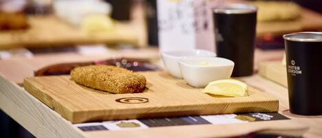 A wooden table with a croissant, a lemon wedge, and a cup of coffee.