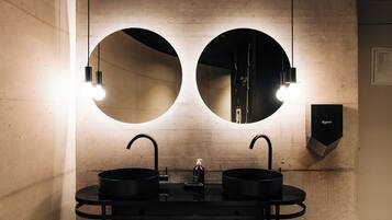 A modern bathroom with two sinks, a mirror, and a Dyson air purifier.