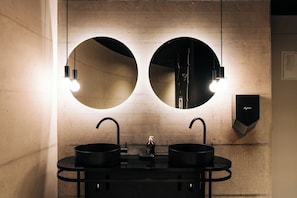 Une salle de bain moderne avec deux lavabos, un miroir et un purificateur d’air Dyson.