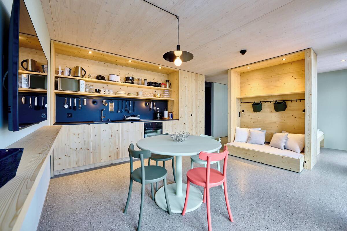 Eine moderne Küche mit Holzschränken, einem Esstisch mit Stühlen und einer integrierten Sofaecke.