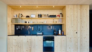 Een compacte keuken met houten kastjes, een inbouwoven en diverse keukengerei en apparaten.