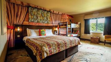 A bedroom with a bunk bed, a patterned bedspread, a headboard with a tapestry, and a window with curtains.