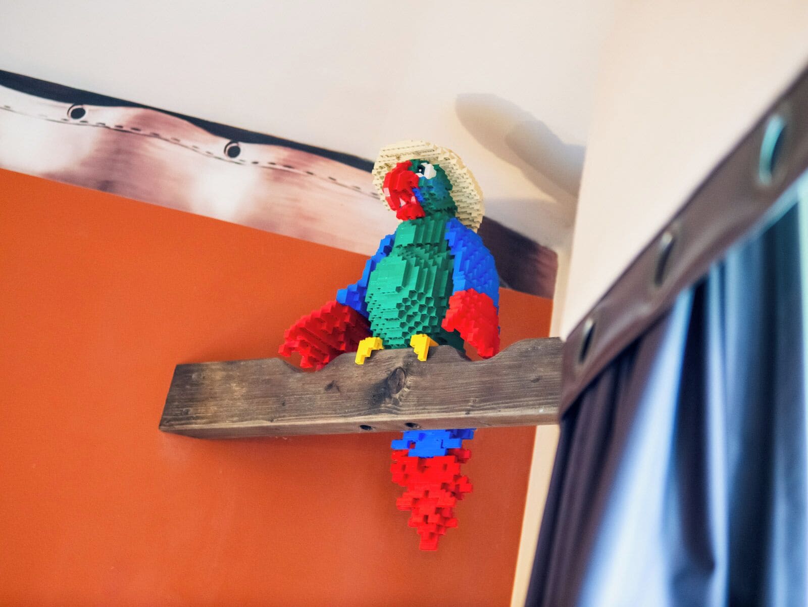 A colorful LEGO bird on a wooden shelf.