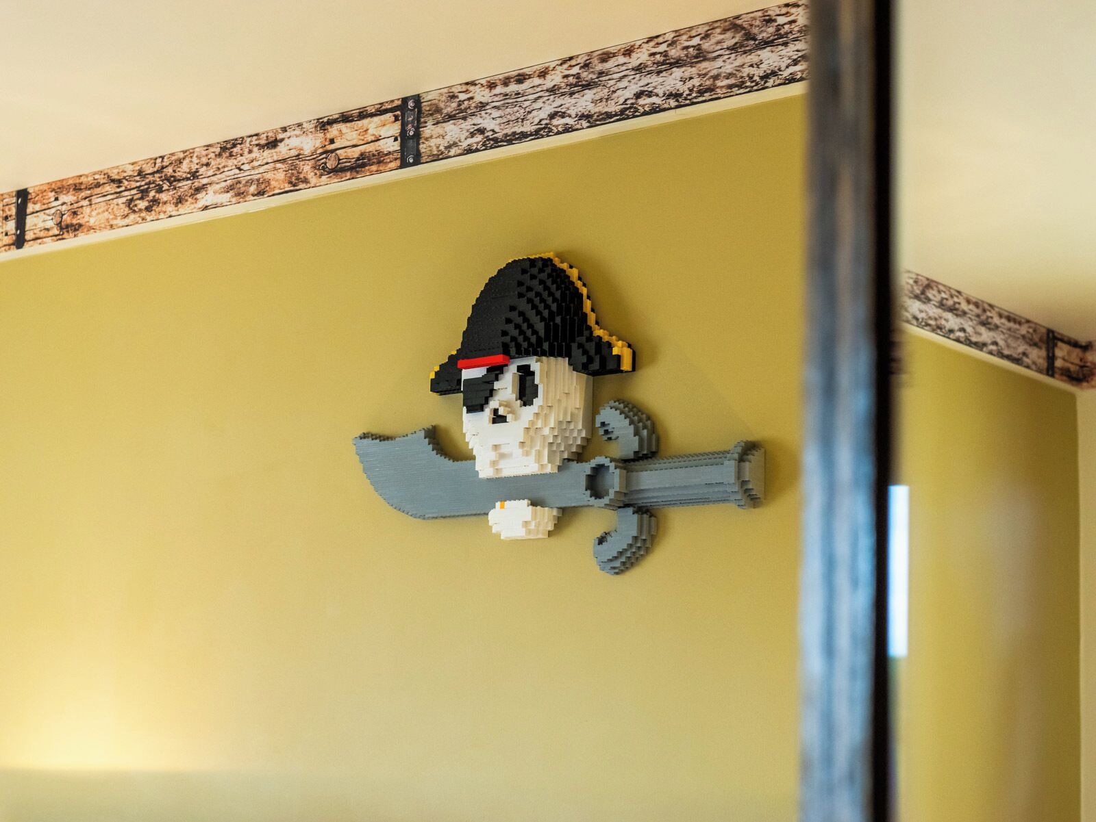 Une figurine de pirate LEGO sur un mur jaune.