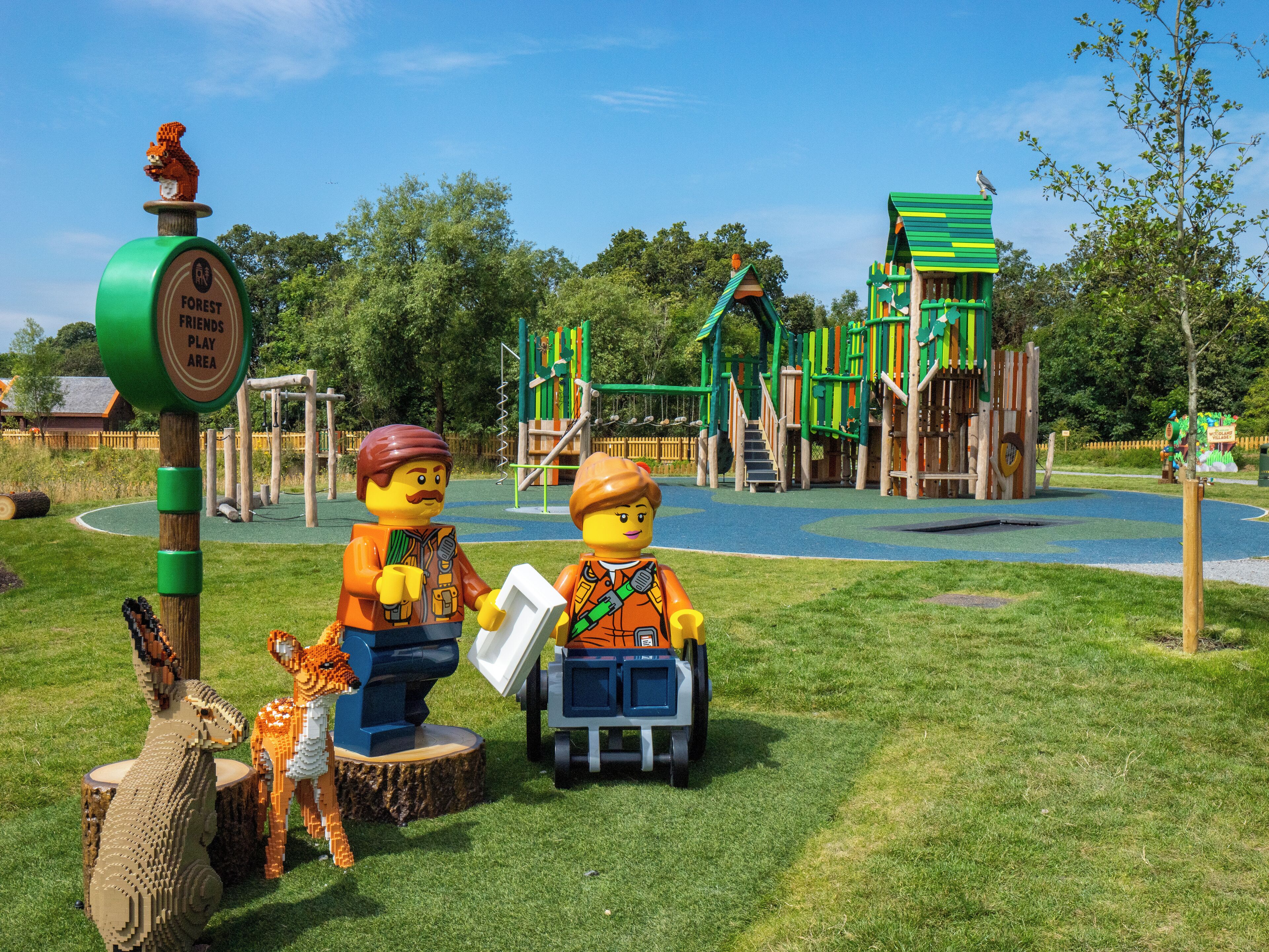 A LEGO play area with a sign, play structures, and LEGO figures.