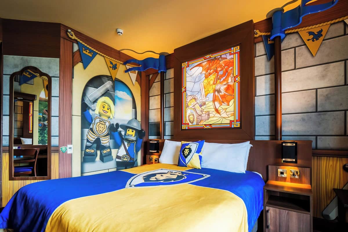 A bedroom with a large bed, a stained glass window, and medieval-themed decorations.