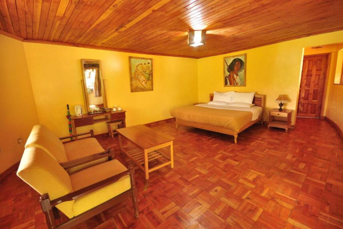 A room with a bed, a desk, a chair, and a wooden ceiling.